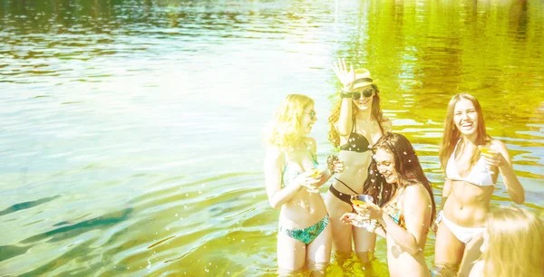 一群美丽的年轻女孩站在水中的海滩上 而持有眼镜 — 图库照片