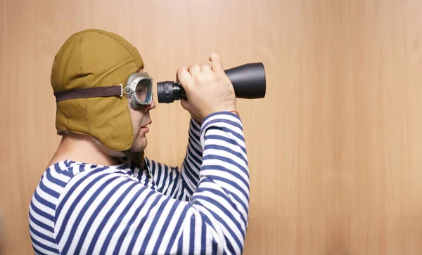 man  holding binoculars. Childhood. Fantasy, imagination. Retro style. serious male playing indoors