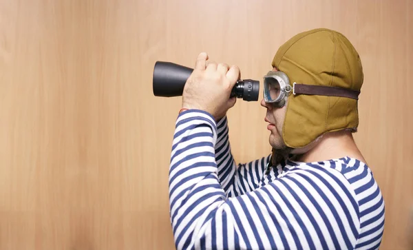 man  holding binoculars. Childhood. Fantasy, imagination. Retro style. serious male playing indoors