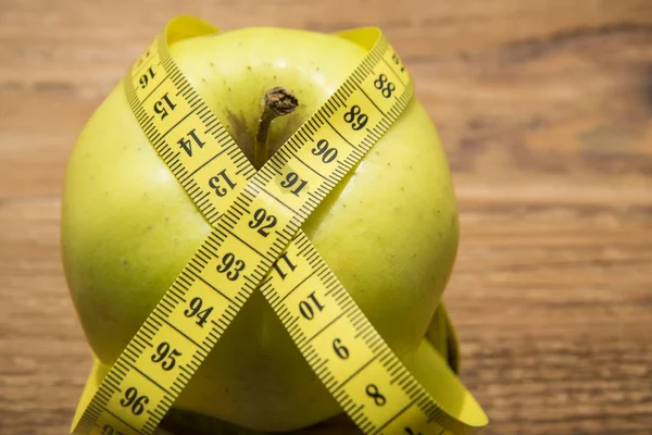 Fita métrica enrolada em torno de uma maçã verde — Fotografia de Stock