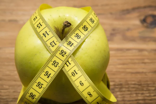 Измерительная лента, обернутая вокруг зеленого яблока — стоковое фото