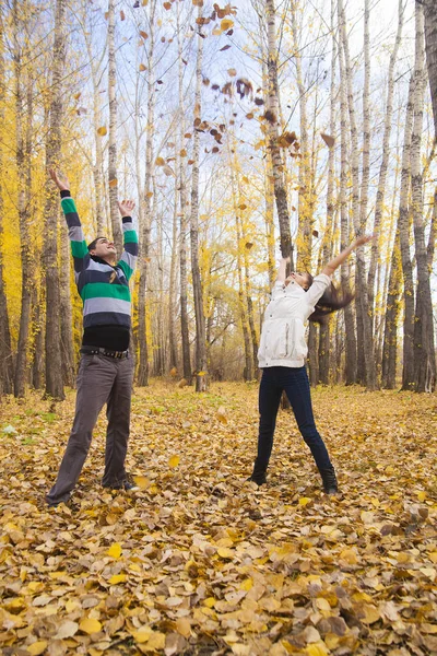 年轻的成人快乐的夫妇投掷秋天叶子在空气中 — 图库照片