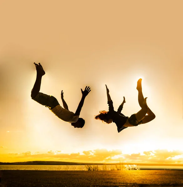 ビーチで家族旅行 男と女のジャンプは 夕日を背景にビーチに落ちて — ストック写真