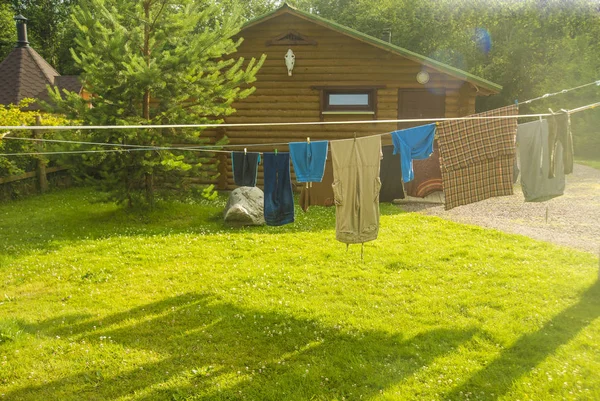 Clothes with colorful pins. Laundry is hung to dry on the yard of old wooden house.