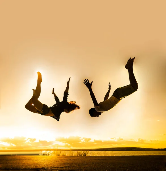 ビーチで家族旅行 男と女のジャンプは 夕日を背景にビーチに落ちて — ストック写真