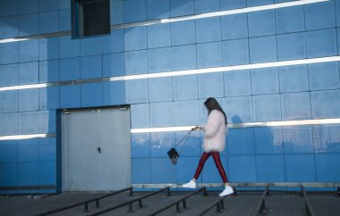 mavi duvar boyunca yürüyen kadın