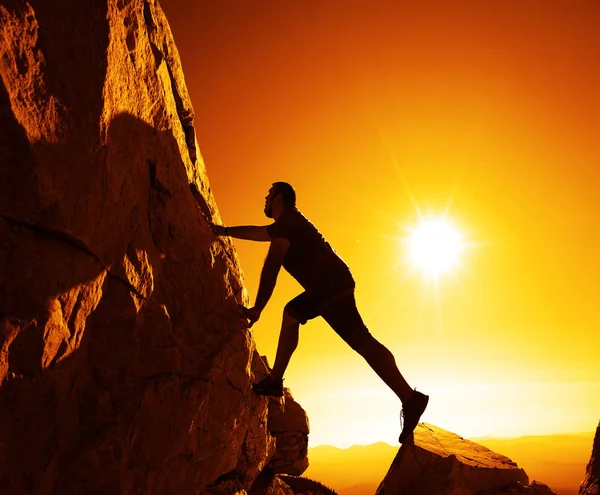 Gündoğumu karşı bir dağın tepesinde bir adam silüeti.     