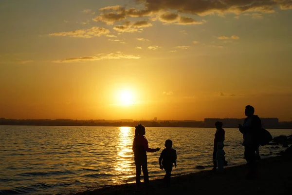 Silhouette of happy family  standing on the beach at the sunset time. Concept of friendly family.