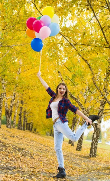 年轻女孩站立在一条腿与其他腿在手和拿着气球 — 图库照片