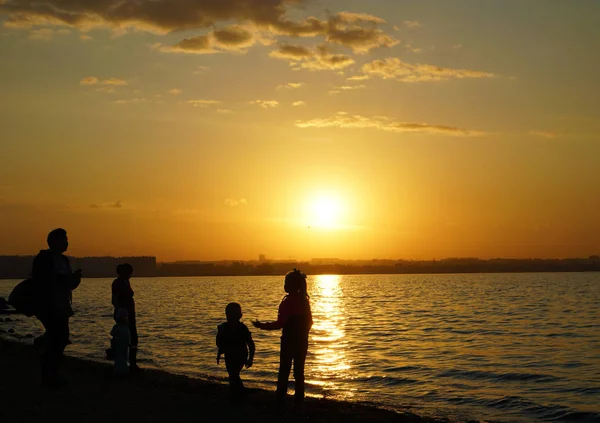 Silhouette of happy family  standing on the beach at the sunset time. Concept of friendly family.