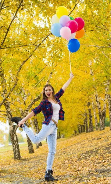年轻女孩站立在一条腿与其他腿在手和拿着气球 — 图库照片