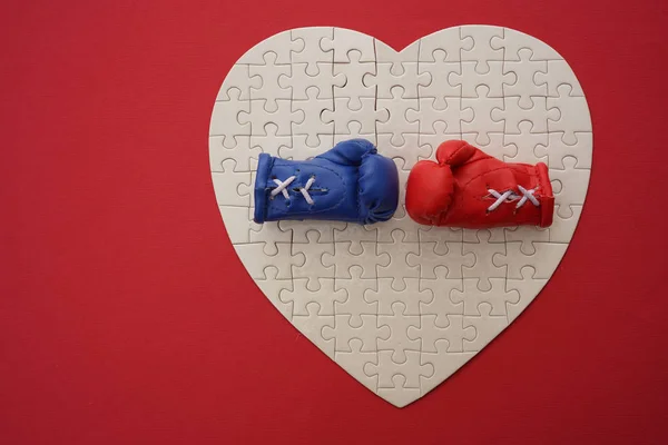 red and blue Boxing gloves on puzzles heart. red paper background. Boxing gloves close up,