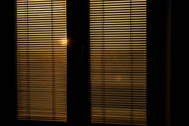 Dikey perdelerin arkasındaki güneş ışığı. 