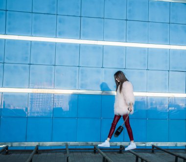 mavi duvar boyunca yürüyen kadın