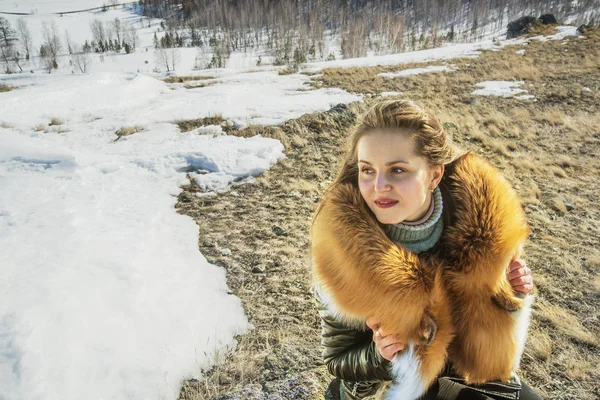 young woman in black coat with  fox ginger fur collar posing. winter season and mountain landscape .