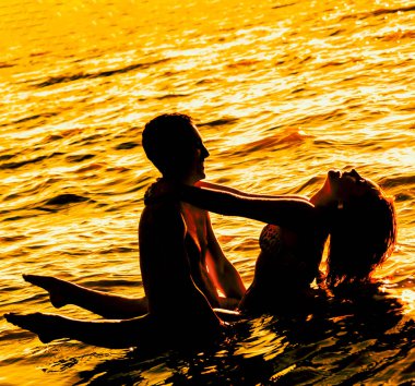Gün batımında suda duran iki genç yetişkin aşıklar 