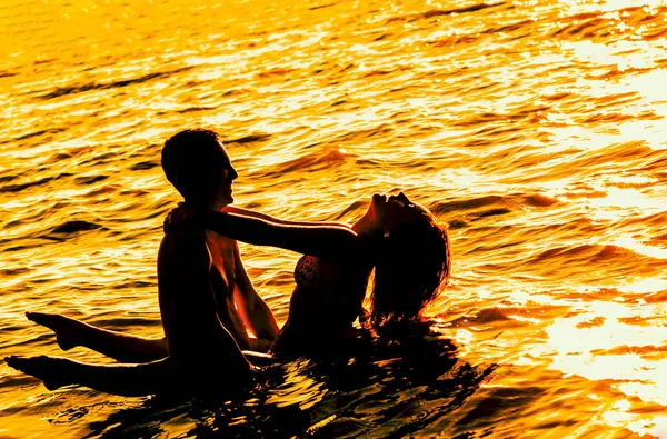 夕暮れ時水に立っている若い大人恋人 — ストック写真