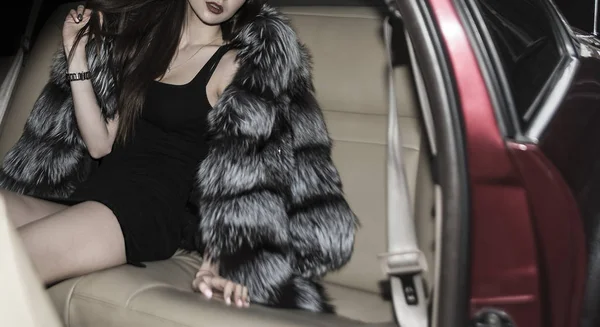 Young brunette woman sitting on a backseat of a luxury car