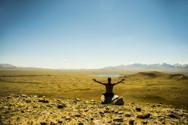 Rock zirvesine oturan adam.