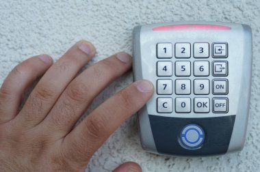 Yakın çekim, kişinin erkek parmak girerek kodu içinde güvenlik sistemi üzerinde mavi gri duvar