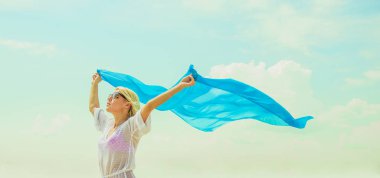 Kadın yaz sahilde poz. Beyaz plaj elbiseli sarışın kız. Mavi bezle sahilde genç güzel kadın