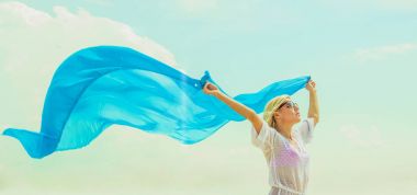 Kadın yaz sahilde poz. Beyaz plaj elbiseli sarışın kız. Mavi bezle sahilde genç güzel kadın