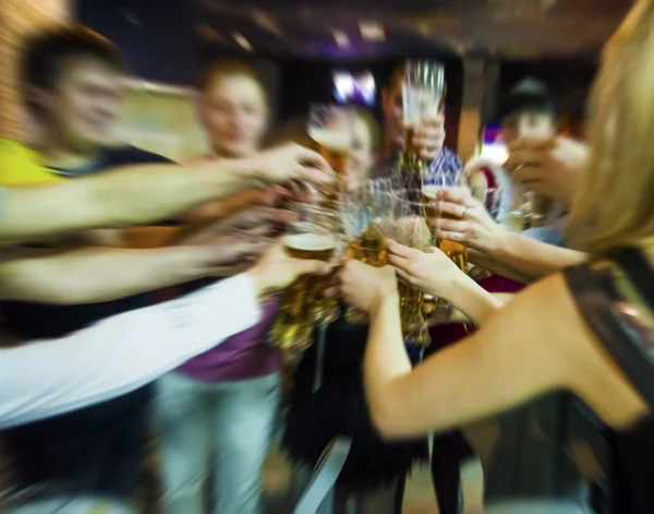 Blurred image. Group of best friends toasting with beer at cafe - Teenagers having fun eating pizza together at lunch time