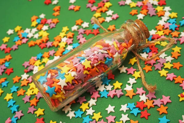 五颜六色的糖果形状的明星在小玻璃瓶与软木 绿纸背景 — 图库照片