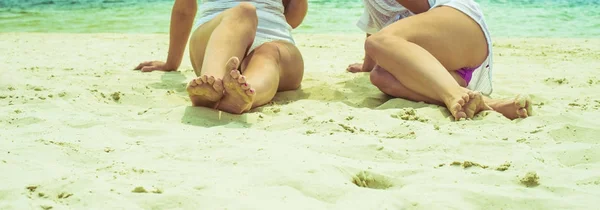 专注于腿部 妇女坐在白色热的沙子反对热带海滩 — 图库照片
