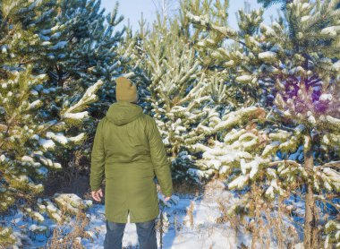 Genç adam kış karlı ormanda ayakta arka, arka görünümü