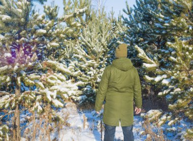 Genç adam kış karlı ormanda ayakta arka, arka görünümü
