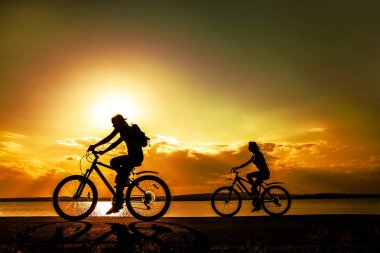 günbatımı Bisiklet sportif arkadaşlar. Siluetleri bisikletçiler kıyısında. Spor doğa arka planda. 