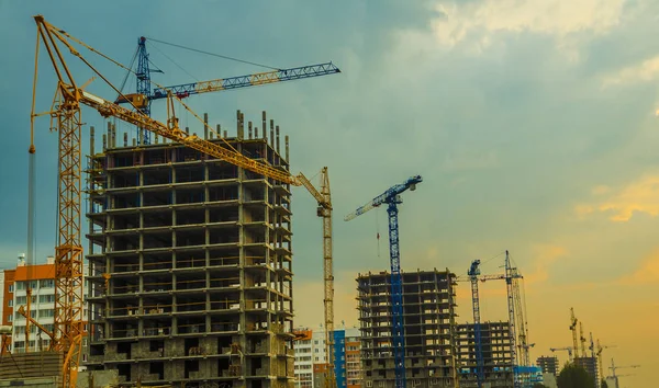 Industrial construction cranes and buildings silhouettes during sunrise