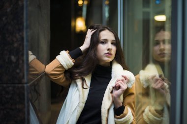 büyük vitrin duran genç yetişkin kadın. Gece çekimi. 