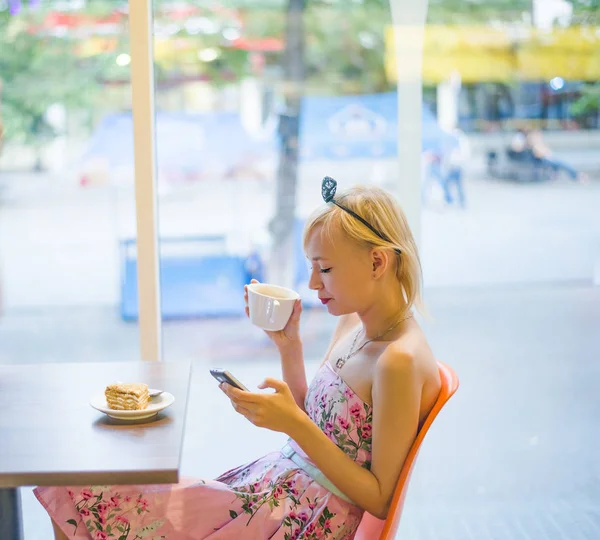 blond woman using  phone in cafe.  Bright sunny morning in cafe.