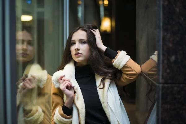 young adult woman standing  near big shop window. Night scene.