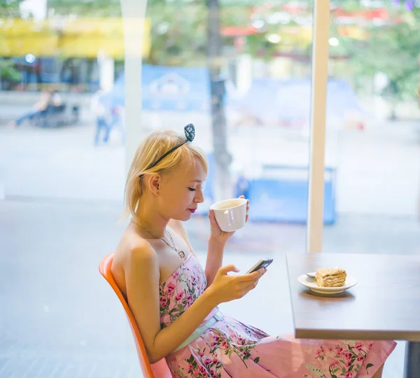 blond woman using  phone in cafe.  Bright sunny morning in cafe.