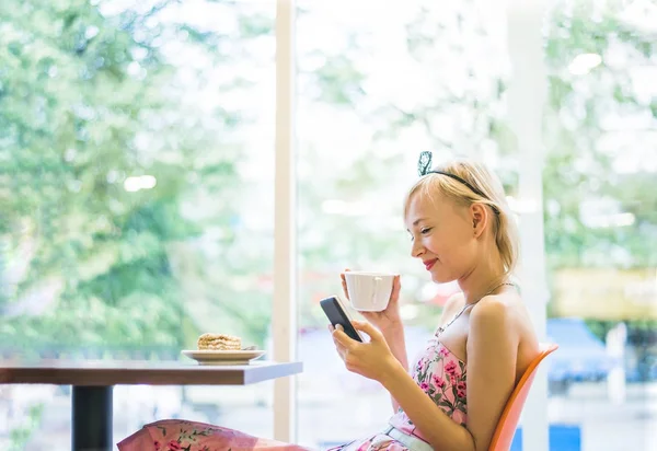 blond woman using  phone in cafe.  Bright sunny morning in cafe.