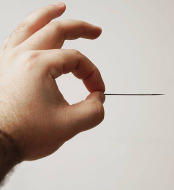 Erkek el beyaz arka plan üzerinde izole iğne ile. El dikiş iğnesi tutarak.