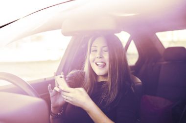 El cep telefonu şeffaf pencere arka plan ile yeni araba içinde tutan güzel Asyalı esmer kadın portresi. Kopya alanı yazıt için. 