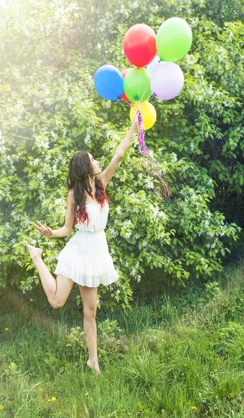 年轻女孩反对盛开的苹果树抱着五颜六色的气球的肖像 — 图库照片