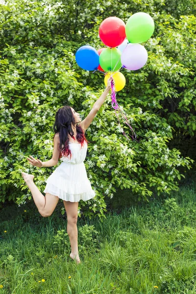 年轻女孩反对盛开的苹果树抱着五颜六色的气球的肖像 — 图库照片