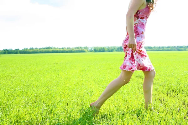 緑の上を歩く女性の脚は フィールド背景を草します 表面無し — ストック写真