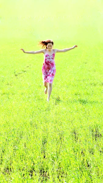 緑の芝生に焦点を当てます。ぼやけ正面赤いドレスの若い女性 — ストック写真