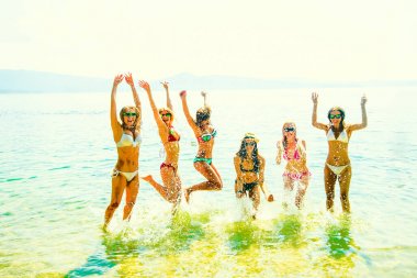 Okyanusta günbatımında atlama kadınlar genç grup. Takım yetişkin kız suya atlama 