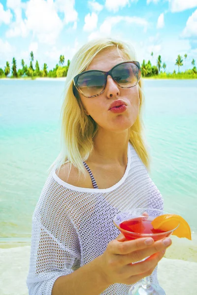 在沙滩上的放松金发女郎的肖像 红色鸡尾酒显示亲吻 — 图库照片