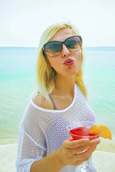 在沙滩上的放松金发女郎的肖像 红色鸡尾酒显示亲吻 — 图库照片