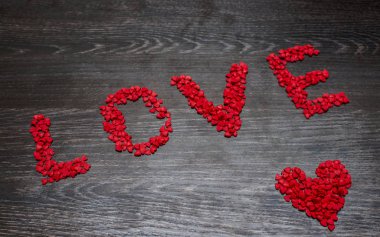 Kırmızı kalp birçok kırmızı Kalpler, bir kelime yapılan - siyah ahşap masa arka plan üzerinde seviyorum