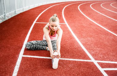 Runner kadın egzersiz önce - açık atış germe. Stadyum egzersiz yaparak spor kız.