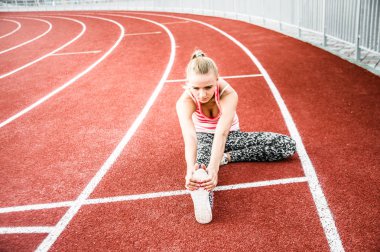 Runner kadın egzersiz önce - açık atış germe. Stadyum egzersiz yaparak spor kız.